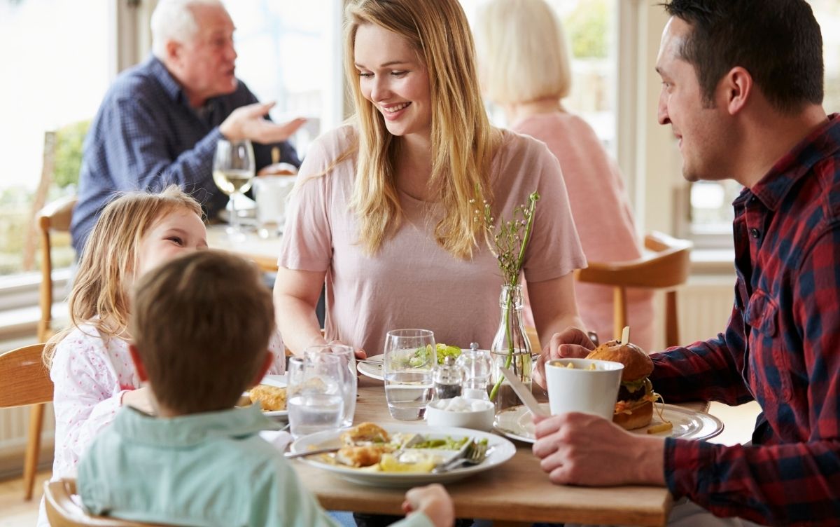Family with two small children eating round a table in a café conservatory