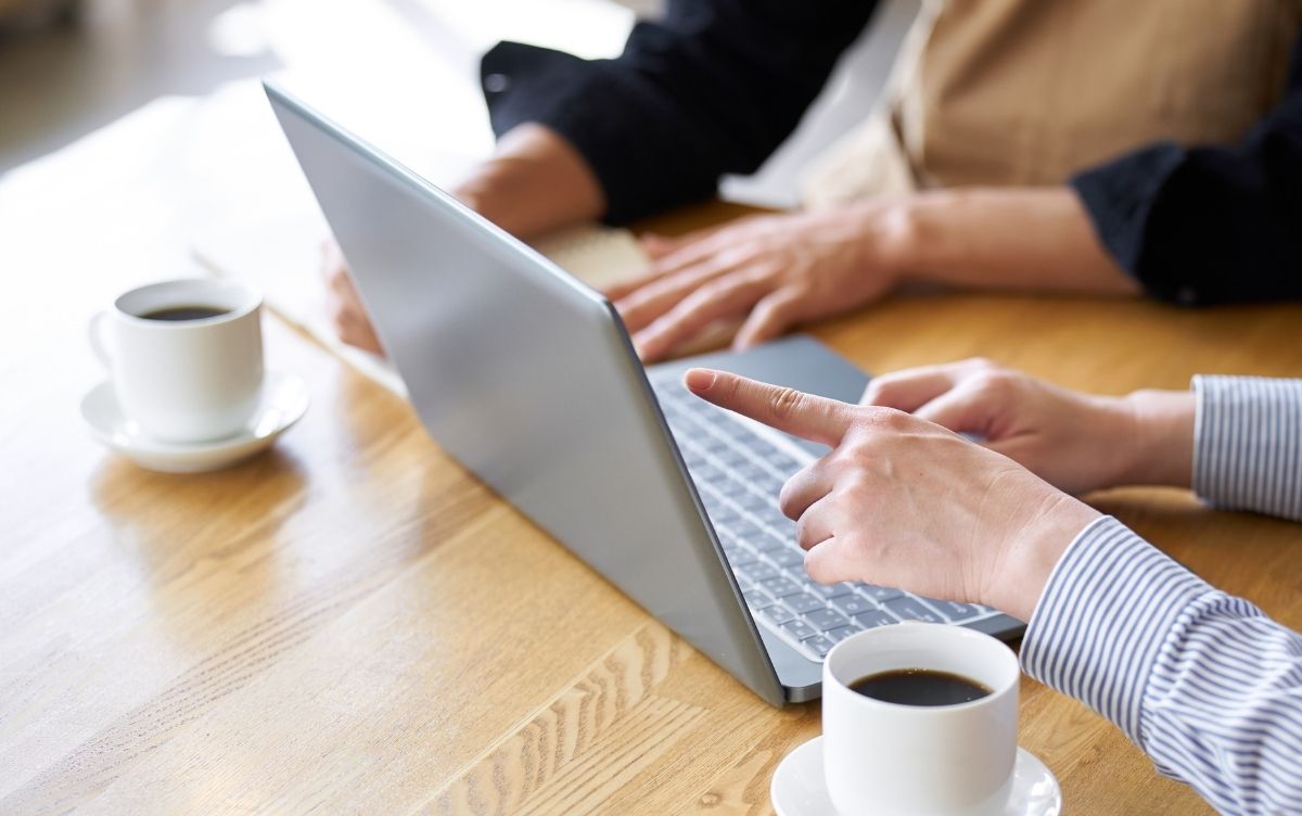 Two hands pointing at a laptop screen