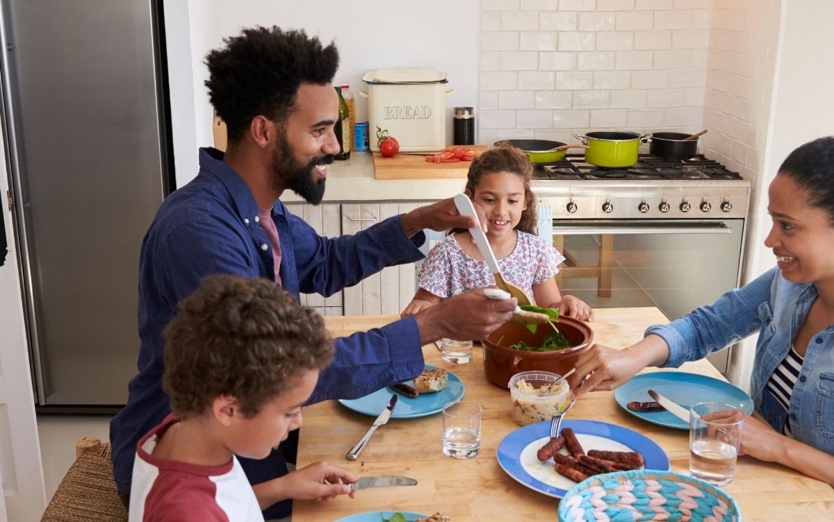 Mum, dad and two children sitting at a dining table at home. They're eating a meal.