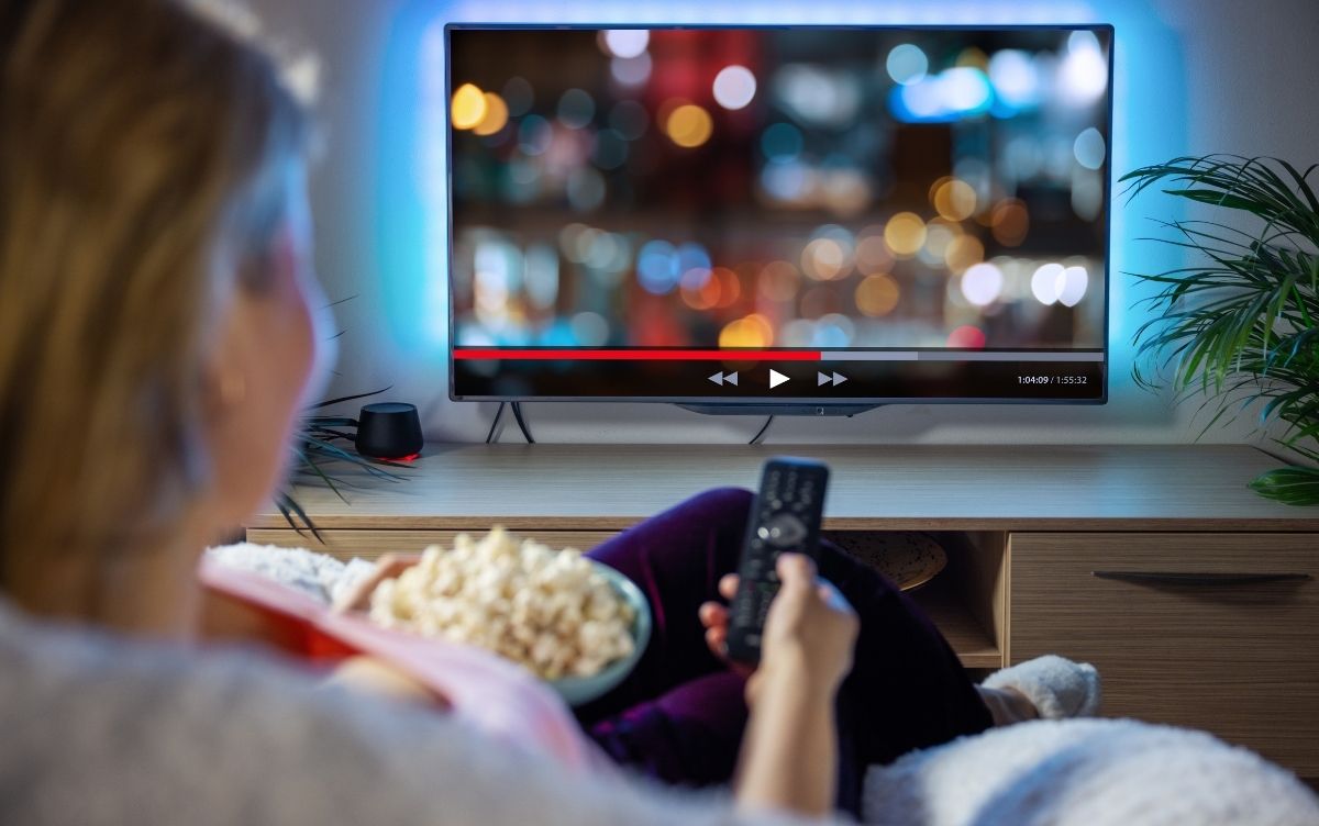 Woman eating healthy snack while watchingTV