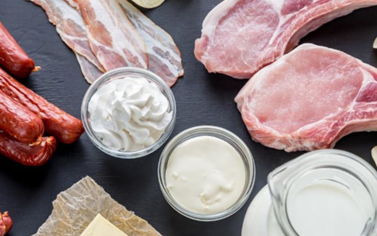 Raw meat and different dairy products such as milk, cheese and cream sitting on a black surface