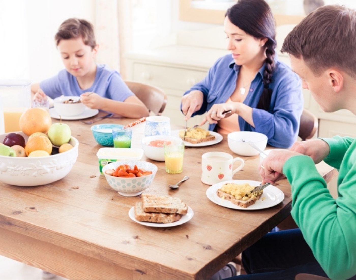Two adults and a child eating a meal at a dining table